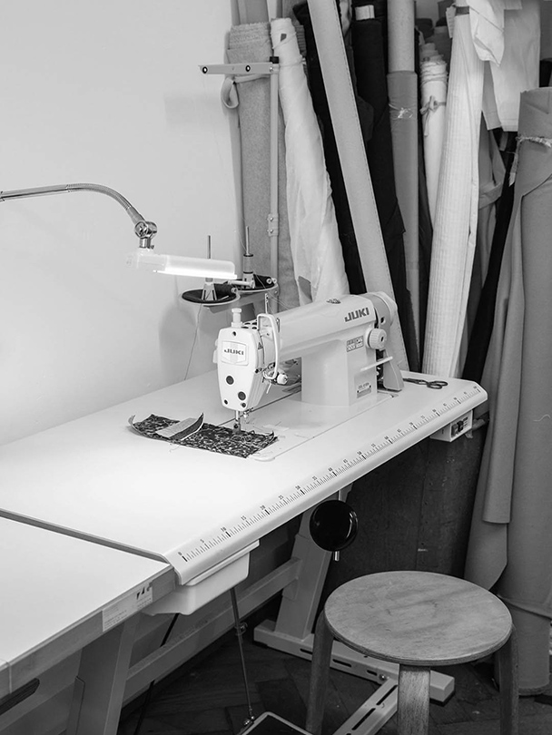 Nähmaschine mit Stoffballen im Hintergrund